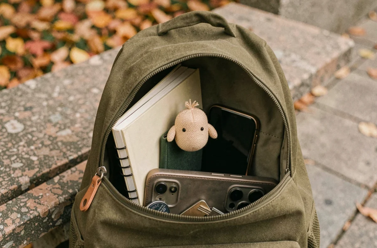 Omamori fixé discrètement à l'intérieur d'un sac à dos en toile verte avec des objets du quotidien